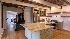 A modern kitchen with a marble countertop, wooden ceiling beams, and white subway tiles. - Hawthorn House at Hound Ears - STUNNING Grandfather views! Pool table! Updated! (Boone)