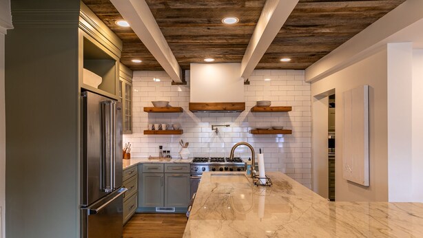 A modern kitchen with a marble countertop, wooden ceiling beams, and built-in shelves. - Hawthorn House at Hound Ears - STUNNING Grandfather views! Pool table! Updated! (Boone)