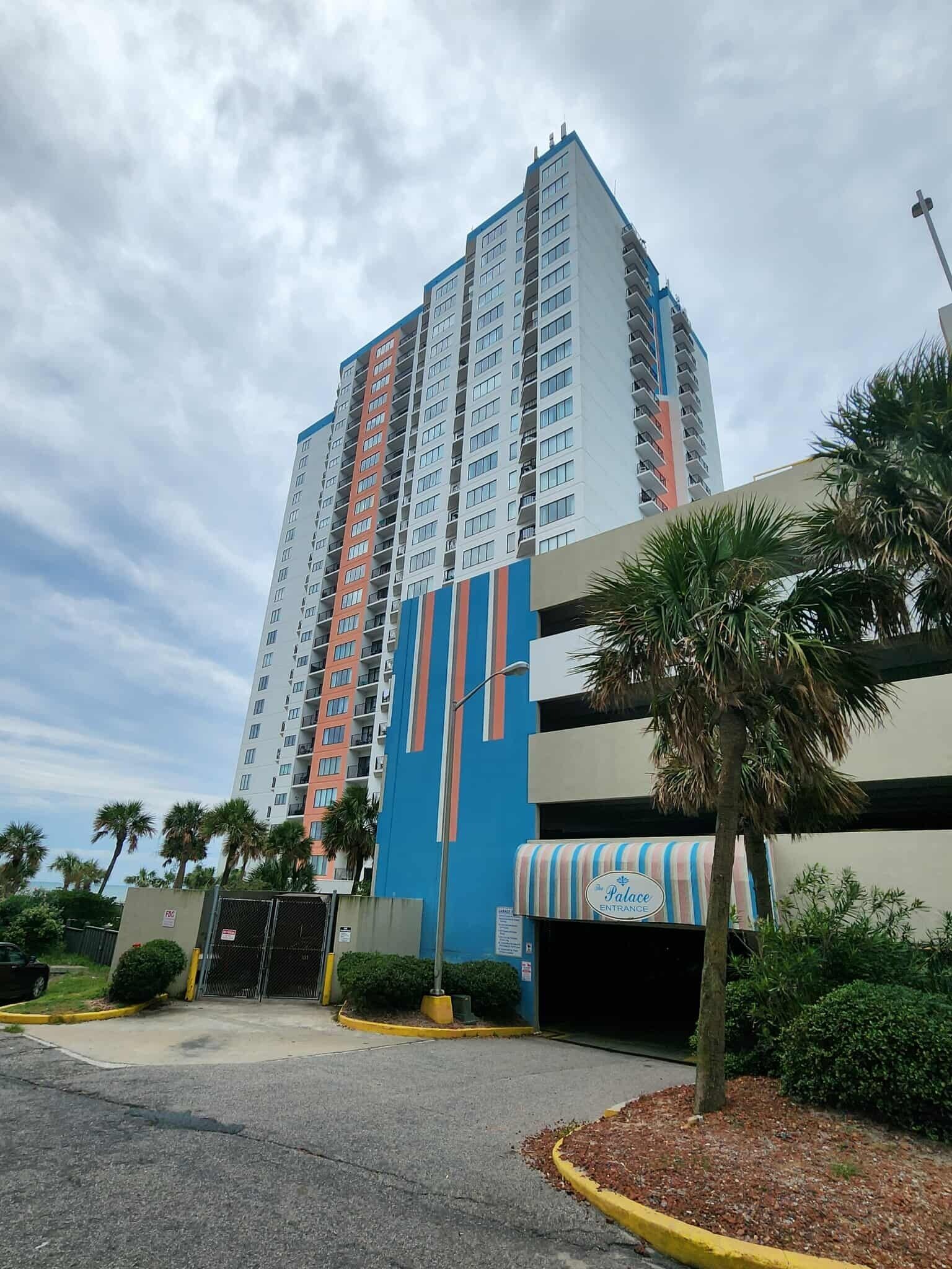 A tall hotel with a modern design, featuring a prominent entrance with a striped awning and a sign.