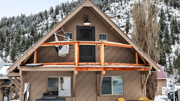 A two-story house with a wooden exterior, a balcony, and a small outdoor seating area. - Modern Mountain Apartment Unit 2 near Durango, CO. (Durango)