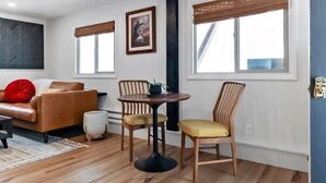 A modern living room with a brown leather sofa, two wooden chairs, a round table with a plant, and a red pillow. - Modern Mountain Apartment Unit 2 near Durango, CO. (Durango)