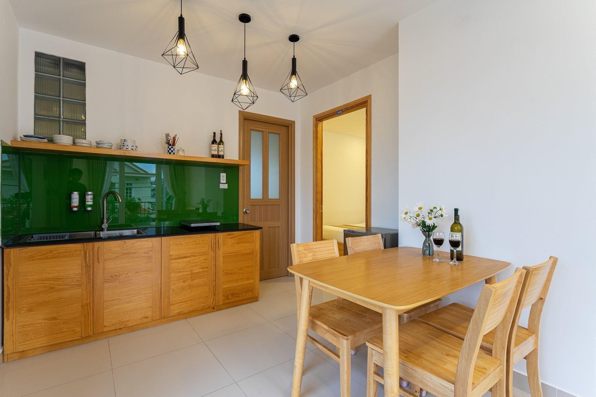 Eine moderne Küche mit Holzausstattung, einer grünen Spritzschutzwand und Pendelleuchten.