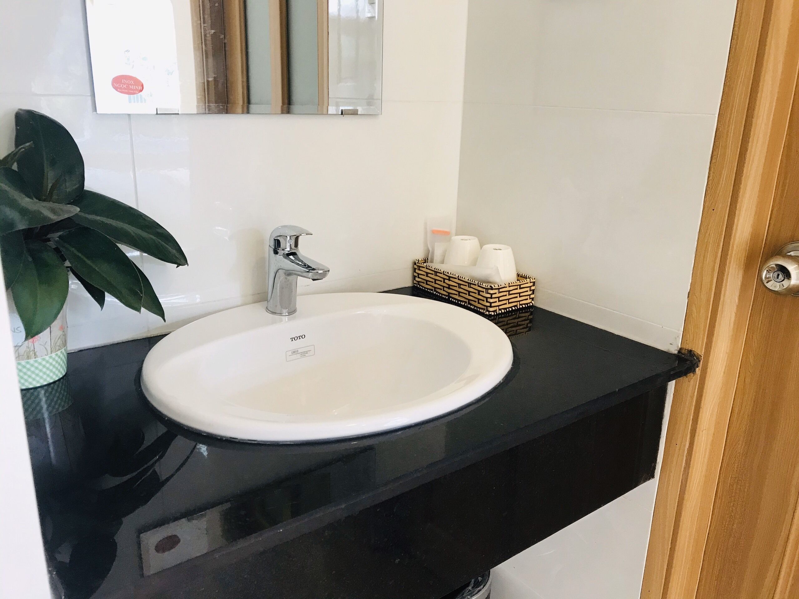 A bathroom with a white sink, black countertop, and a wooden door.