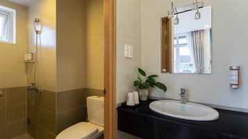 A bathroom with a toilet, shower, sink, and mirror.
