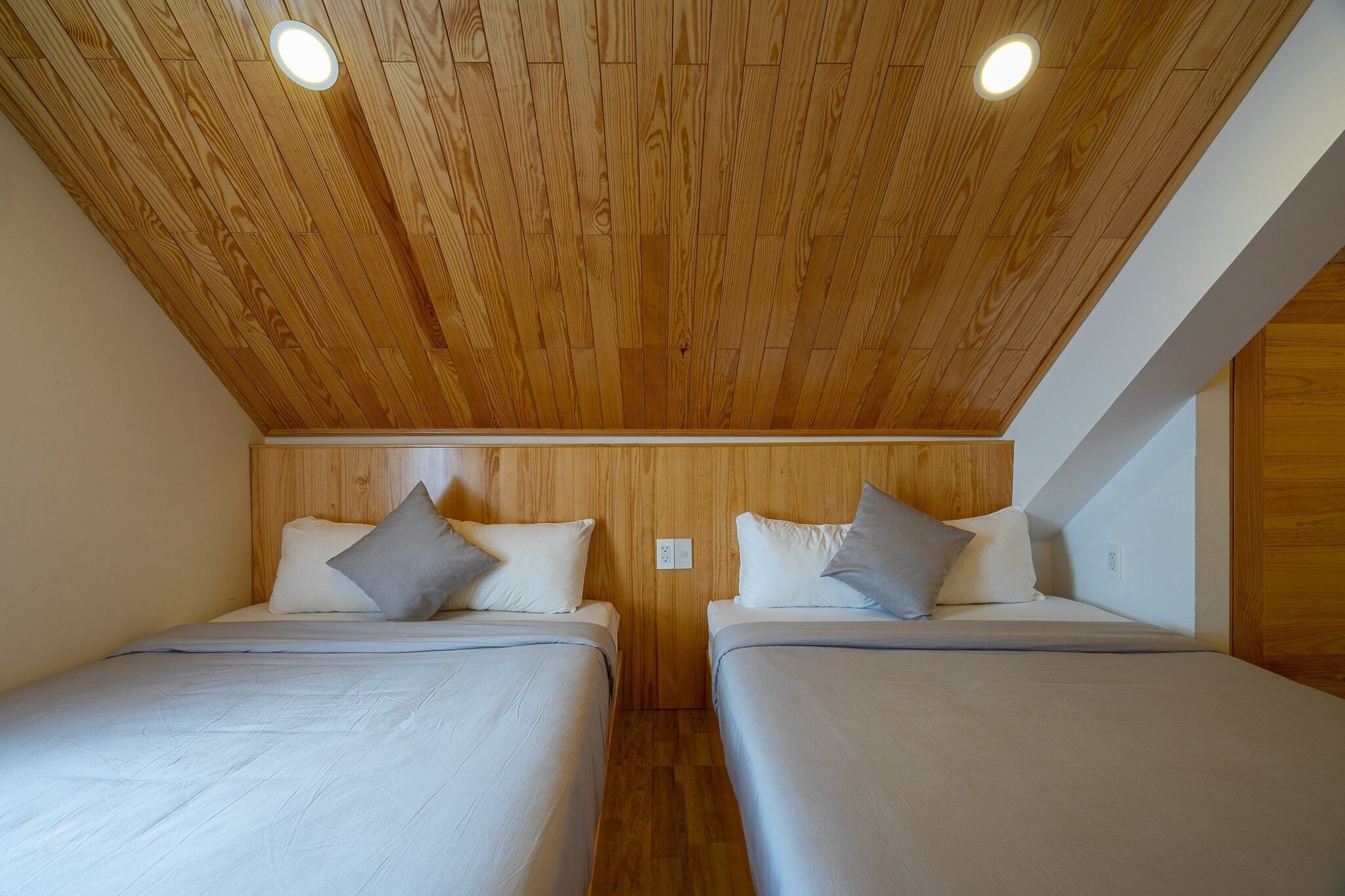 Habitación con dos camas, techo de madera e iluminación empotrada.