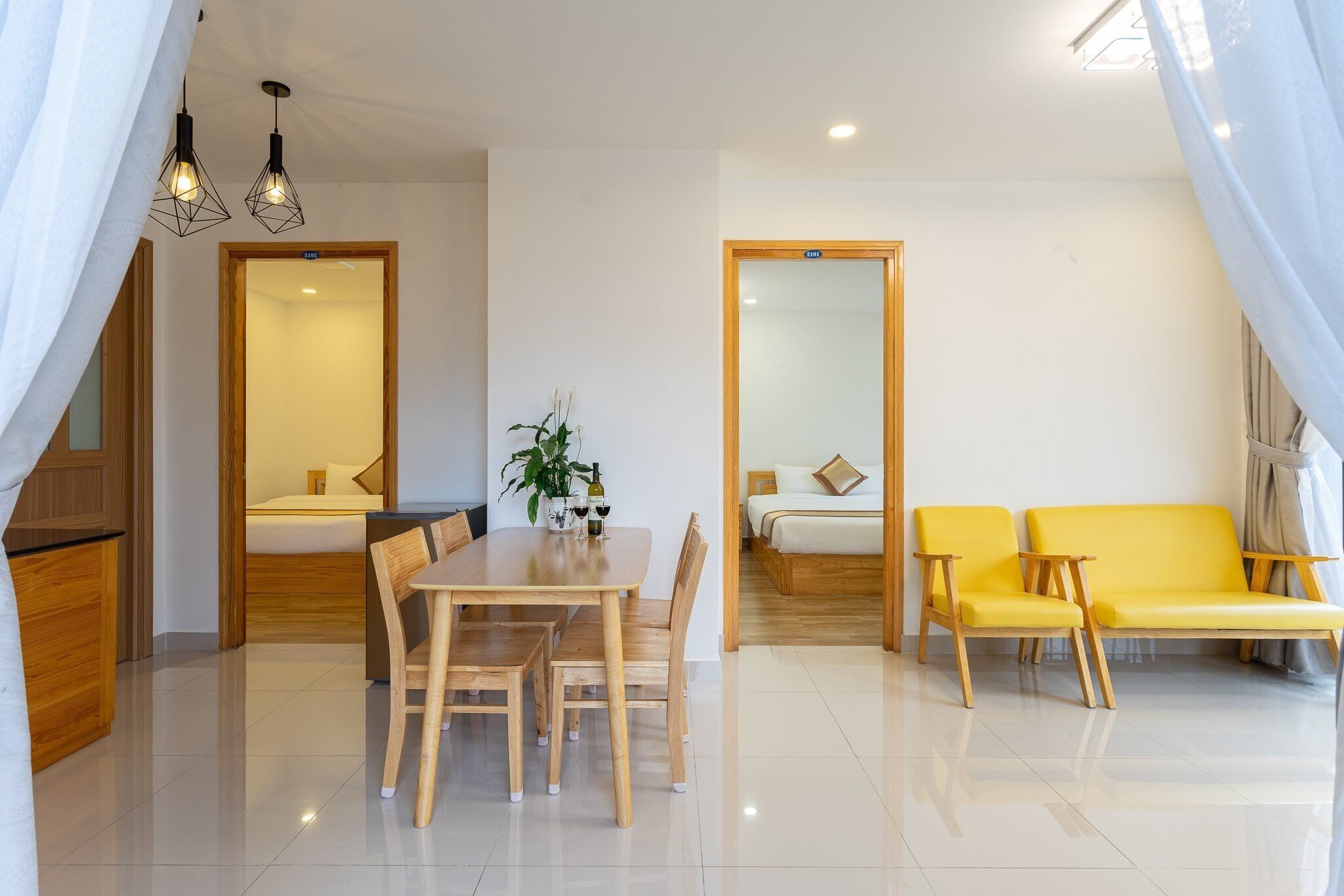 Una habitación de hotel moderna con zona de comedor, un conjunto de sofás y una cama.