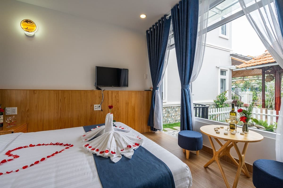 Et hotelværelse med seng, fjernsyn, balkon med bord og stole samt udsigt ud.
