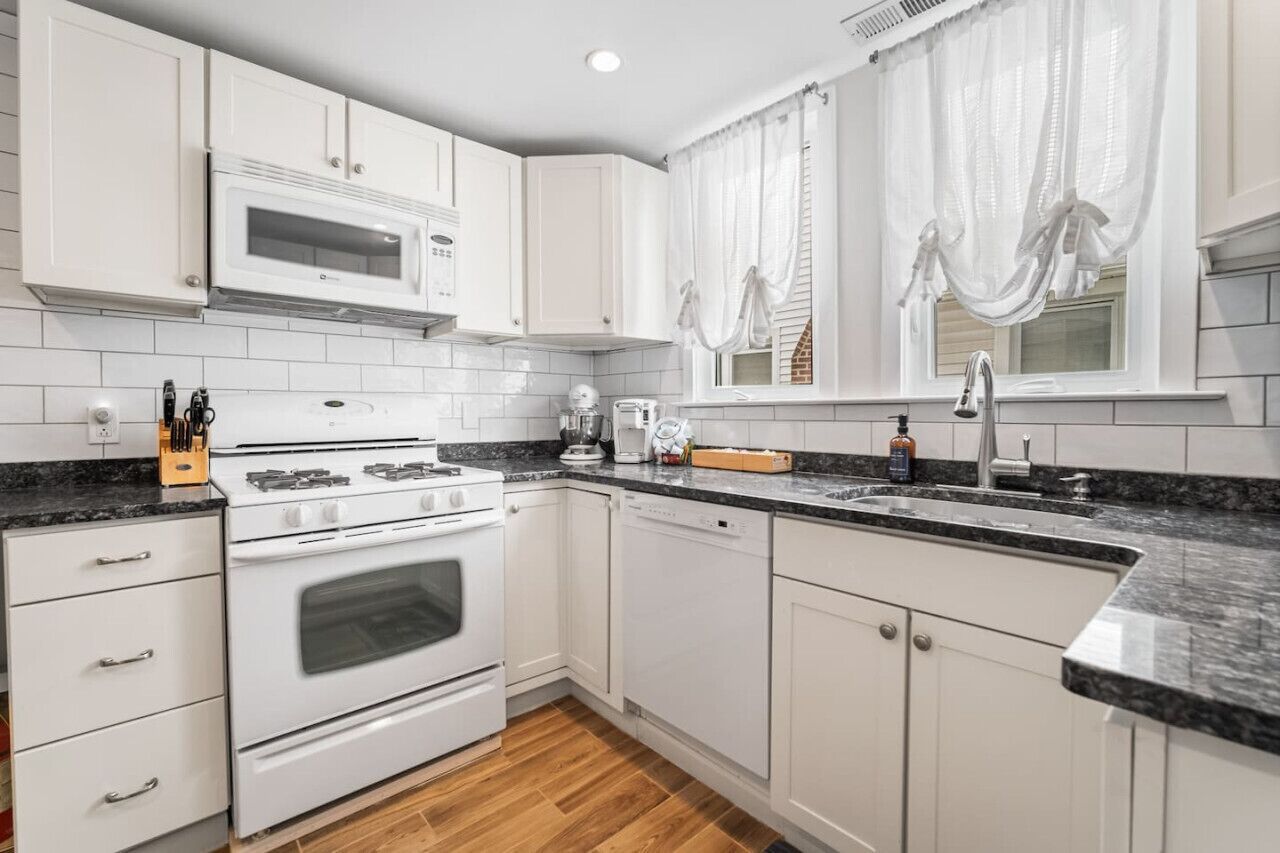 A modern kitchen with white cabinetry, a built-in microwave, a stove, and a dishwasher.