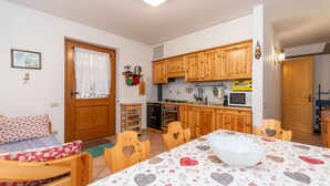 A compact living space with a kitchenette, a dining area with heart-patterned tablecloths, and a bed with floral bedding.