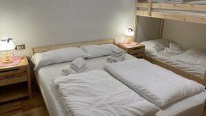 A room with bunk beds, two bedside tables with lamps, and neatly folded towels.