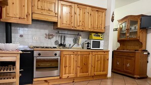 A kitchen with wooden cabinets, a stove, an oven, a microwave, and a cabinet with glass doors.