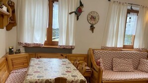 A cozy room with a wooden dining table and chairs, a sofa, and a clock on the wall.