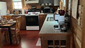 A cozy cabin-style kitchen with wooden walls and a tiled floor. - Beautiful Rustic Cabin 
Just 10 Minutes to Granbury square  (Granbury)
