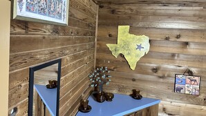 A wooden cabin interior with a framed photo, a map of Texas, and decorative items on a blue shelf. - Beautiful Rustic Cabin 
Just 10 Minutes to Granbury square  (Granbury)