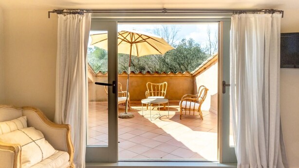 A room with a sliding glass door leading to an outdoor patio with a table, chairs, and an umbrella.