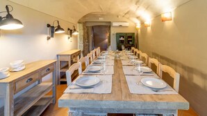A long dining table set for a meal with chairs on both sides, wooden walls, and wall-mounted lighting.