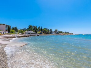 Une plage à l’eau claire, une tour de surveillance pour les sauveteurs et un bâtiment doté d’une piscine.