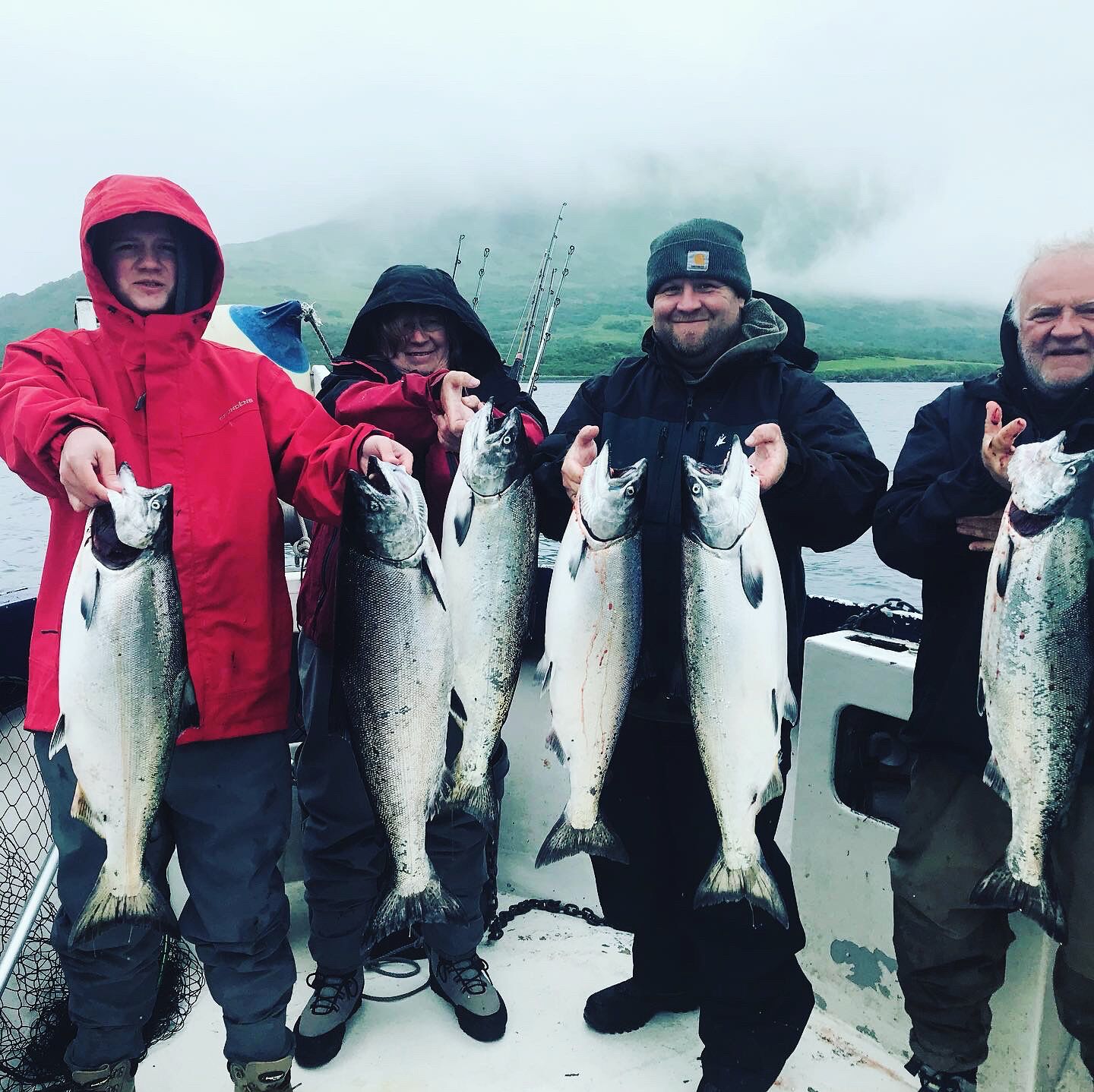 A group of people on a boat holding fish.