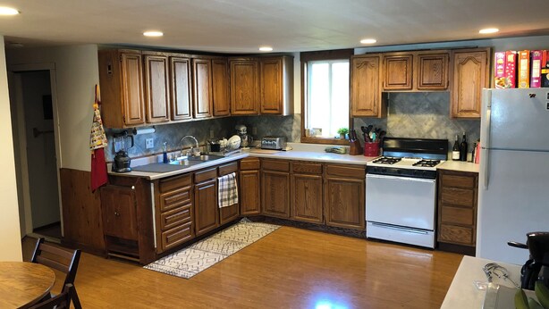 A kitchen with wooden cabinets, a stove, a sink, and a refrigerator.