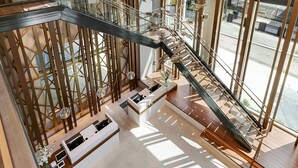 A modern interior with a glass staircase, wooden accents, and a reception desk.