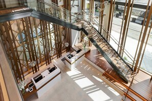 A modern interior with a glass staircase, wooden accents, and a reception desk.