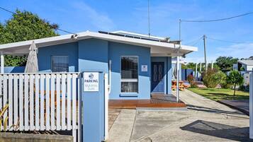 A blue building with a white fence labeled "PARKING Mykonos Suite."