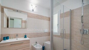 A modern bathroom with a glass shower enclosure, a sink with a mirror, and a toilet. - Villa Blue Kalinda - Sardinia Unlimited (Rena Majore)