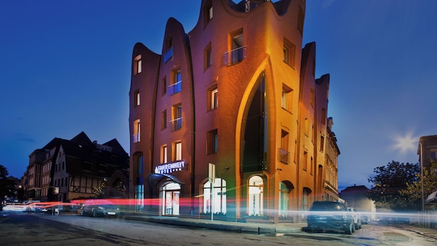 Um hotel com estilo arquitetônico marcante, com janelas em arco e uma entrada imponente.