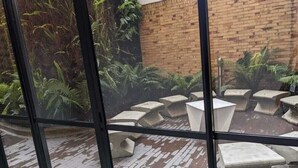 A courtyard with a brick wall, ferns, and a circular seating area with concrete planters. - Apartamentos Quinta Avenida (Bogotá)