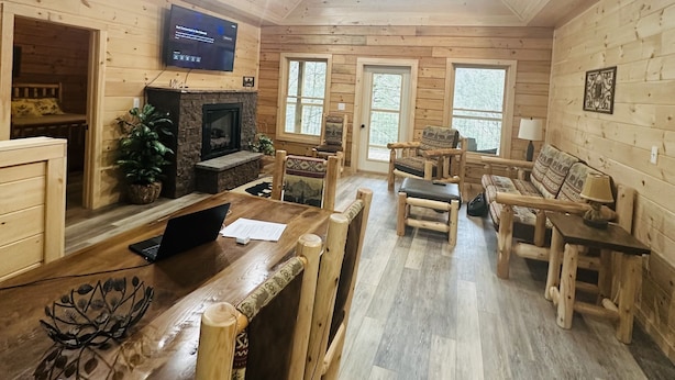 A cozy cabin interior with wooden walls, a wooden dining table, and a fireplace. - Misty Mountain View @Smokies  #Xplorietickets:  Explore More, Experience More!! (Gatlinburg)