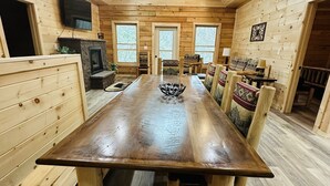 A wooden interior with a long dining table, benches, a fireplace, and a TV mounted on the wall. - Misty Mountain View @Smokies  #Xplorietickets:  Explore More, Experience More!! (Gatlinburg)