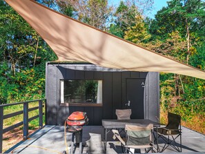 A small cabin with a deck, a table, and two chairs. - Bulls Camp (Narusawa)
