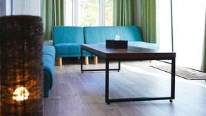 A modern living room with a teal sofa, a wooden coffee table, and green curtains. - Bulls Camp (Narusawa)