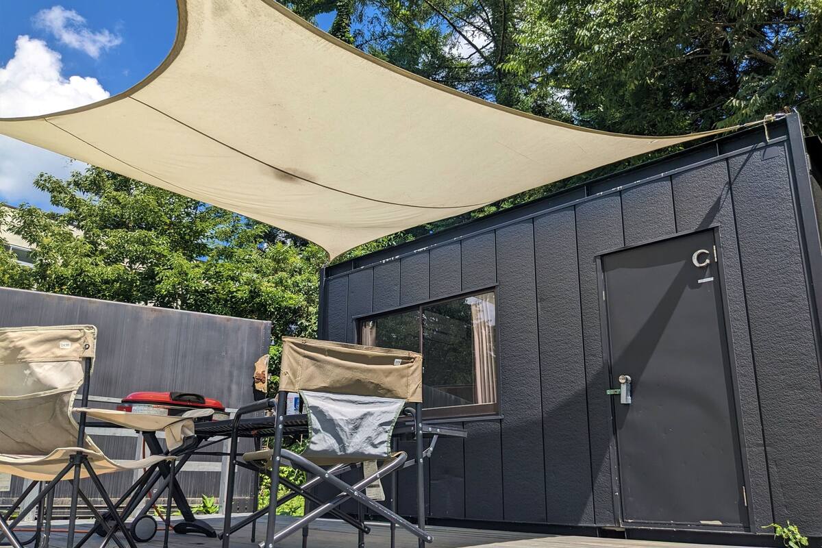A small, modern outdoor structure with a dark exterior, a door, and a window.