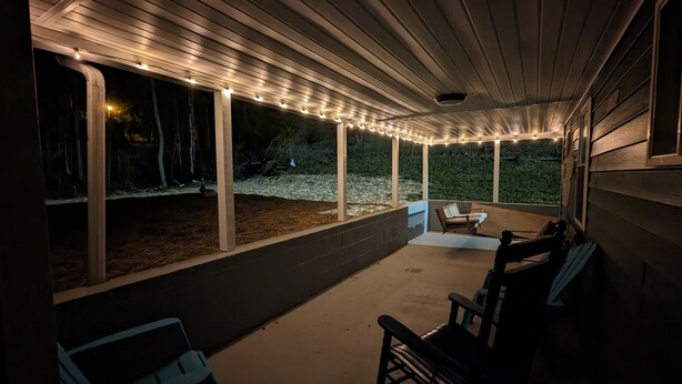 A covered outdoor area with string lights, a concrete floor, and a view of a wooded area. - Trail Riders Retreat! Hatfield McCoy Trails. Private Pool. Loads of Parking!  (Williamson)