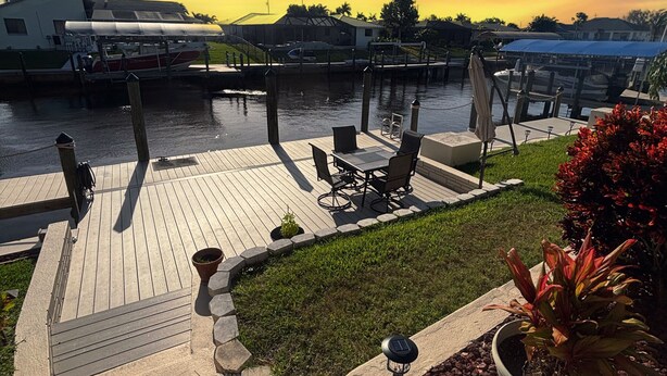 A waterfront patio with a wooden deck, outdoor seating, and a view of the water. - Summer vacation, dream destination w heated pool boat dock kids and pets welcome (Cape Coral)