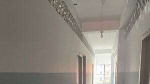 A hallway with a star-patterned floor, doors on both sides, and a window at the end. - Hotel Sharnali (Khulna)