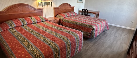 Una habitación de hotel con dos camas, una mesita de noche, una silla y una pequeña mesa.