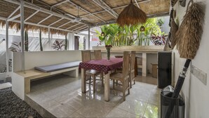 A covered outdoor dining area with a table and chairs, a bench, and a ceiling fan. - Gajah Villa by Betterplace (Canggu)