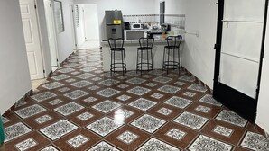A kitchen with a white countertop, three bar stools, and a ceiling fan.