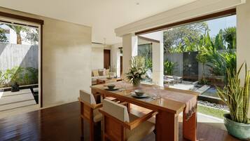 Un comedor moderno con una mesa y sillas de madera, un jarrón con flores y vistas al jardín exterior.