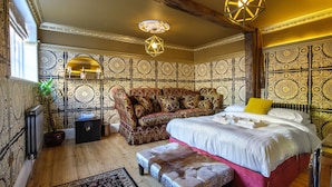 Una camera da letto con un letto grande, un divano e una parete decorativa.