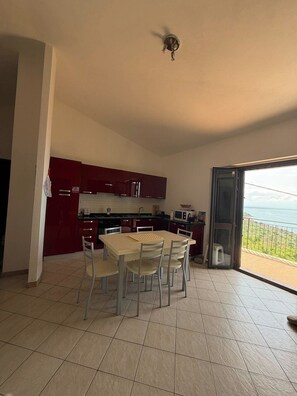 Une cuisine avec une table et des chaises, une vue sur la mer et une porte-fenêtre coulissante.