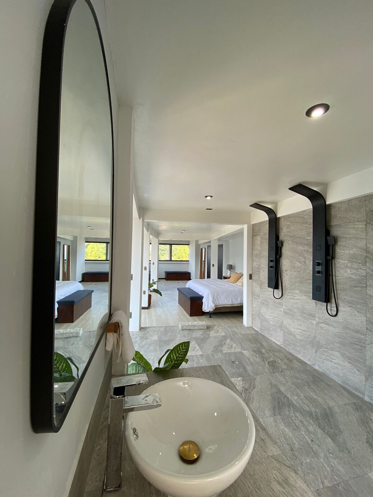 A modern bathroom with a large mirror, a sink, and a shower area.