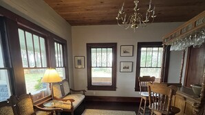 Una habitación acogedora con techo de madera, candelabro, alfombra estampada y un banco con lámpara.