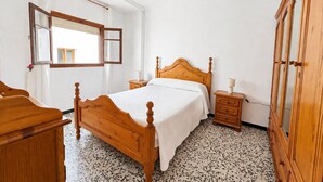 A bedroom with a wooden bed, a nightstand, a dresser, a mirror, and a ceiling fan. - Apartment El Arco, in Conil. (Conil)