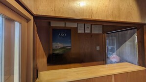 Una reception in legno con un poster di un paesaggio suggestivo, rivestimenti in legno e una porta in vetro.