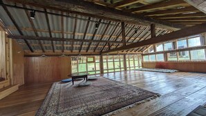 Un'ampia stanza con soffitto alto, travi in legno e grandi finestre.