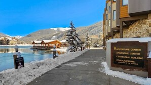 Een besneeuwde pad dat leidt naar een gebouw met de tekst 'Adventure Center Argentine Center Centennial Building Condominiums: Argentine & The Seasons'.