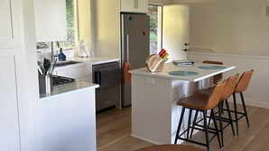 Eine moderne Küche mit weißen Schränken, einer zentralen Kochinsel mit Barhocker und einem Edelstahlkühlschrank.